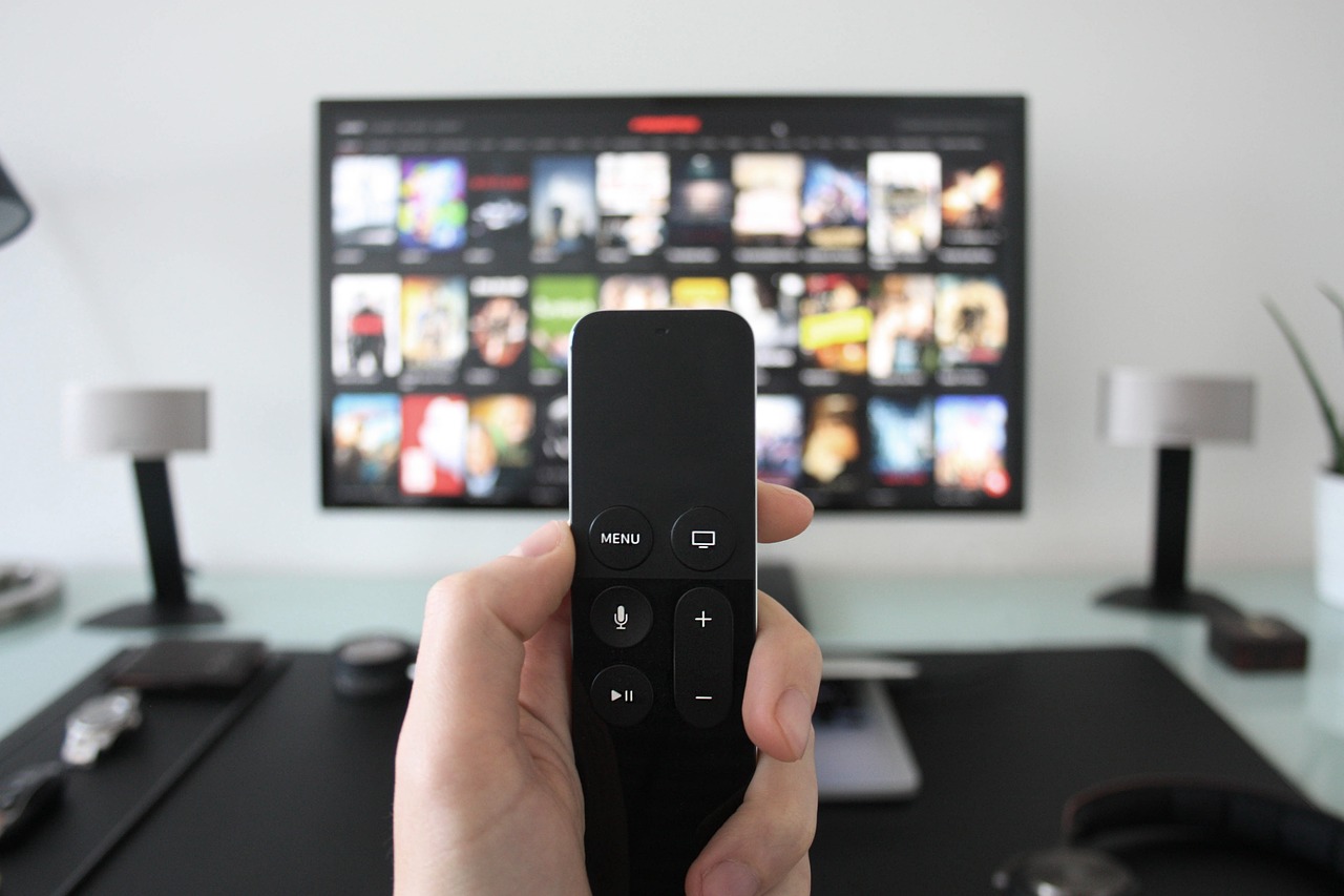 A person can't decide which channel to view on a flat screen TV. Information overload is a sign of the times