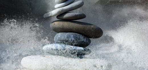 A stack of rocks is being knocked out by a surf. The synergy created can represent energetic PTSD